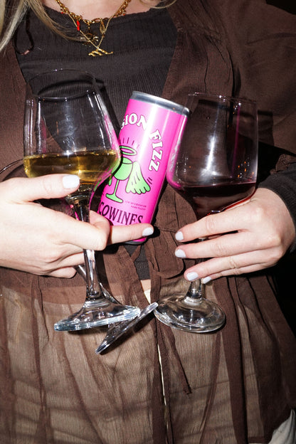 Person holding a Session Fizz organic canned wine and a wine glass at an evening event by Loco Wines