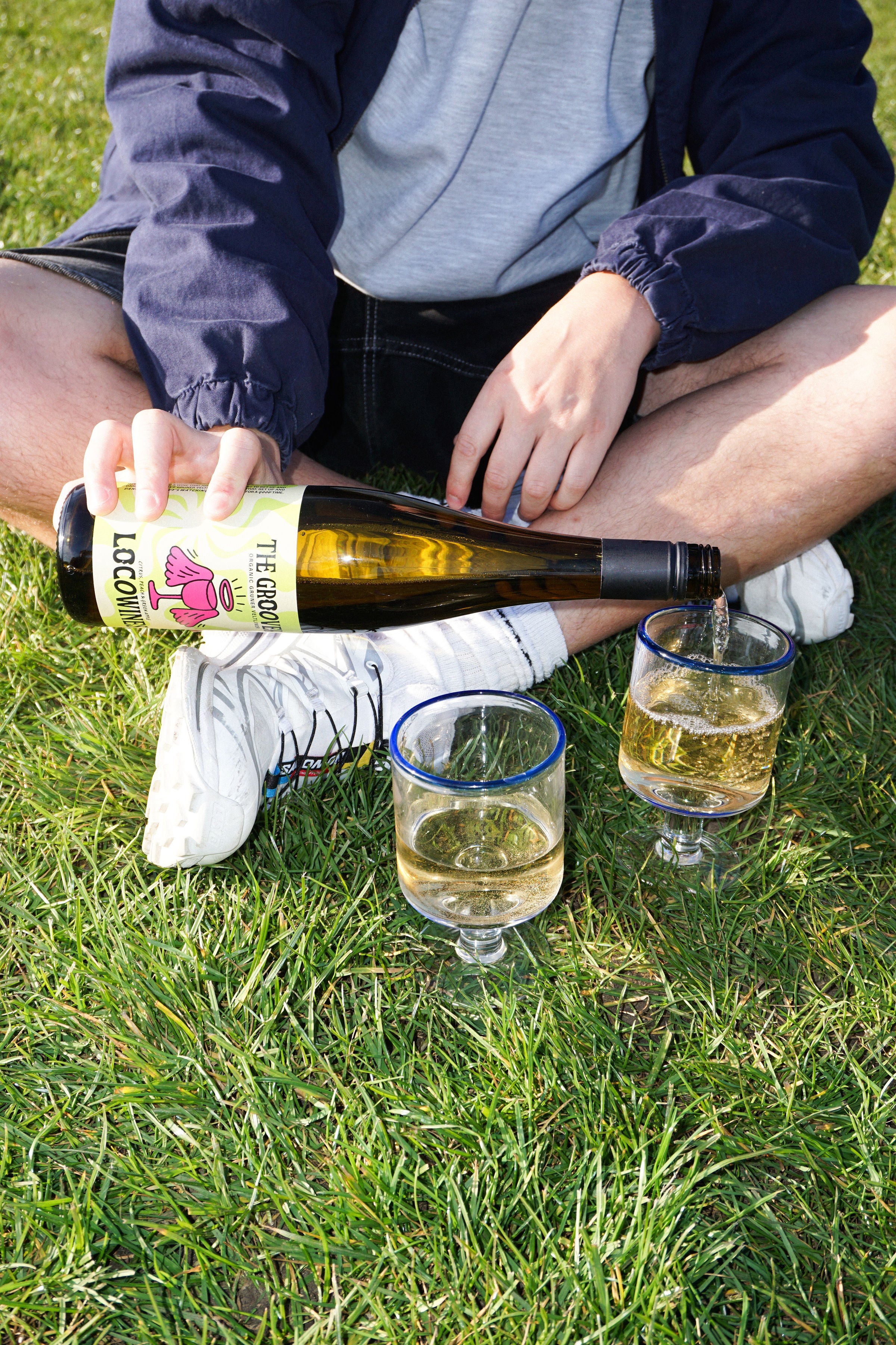 The Groover organic white wine being poured into glasses on the grass at a sunny outdoor picnic by Loco Wines